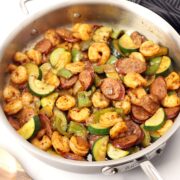 A saute pan filled with shrimp, sausage, and veggies.