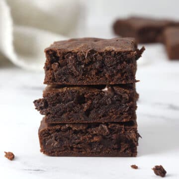 A stack of three chocolate brownies on a countertop.
