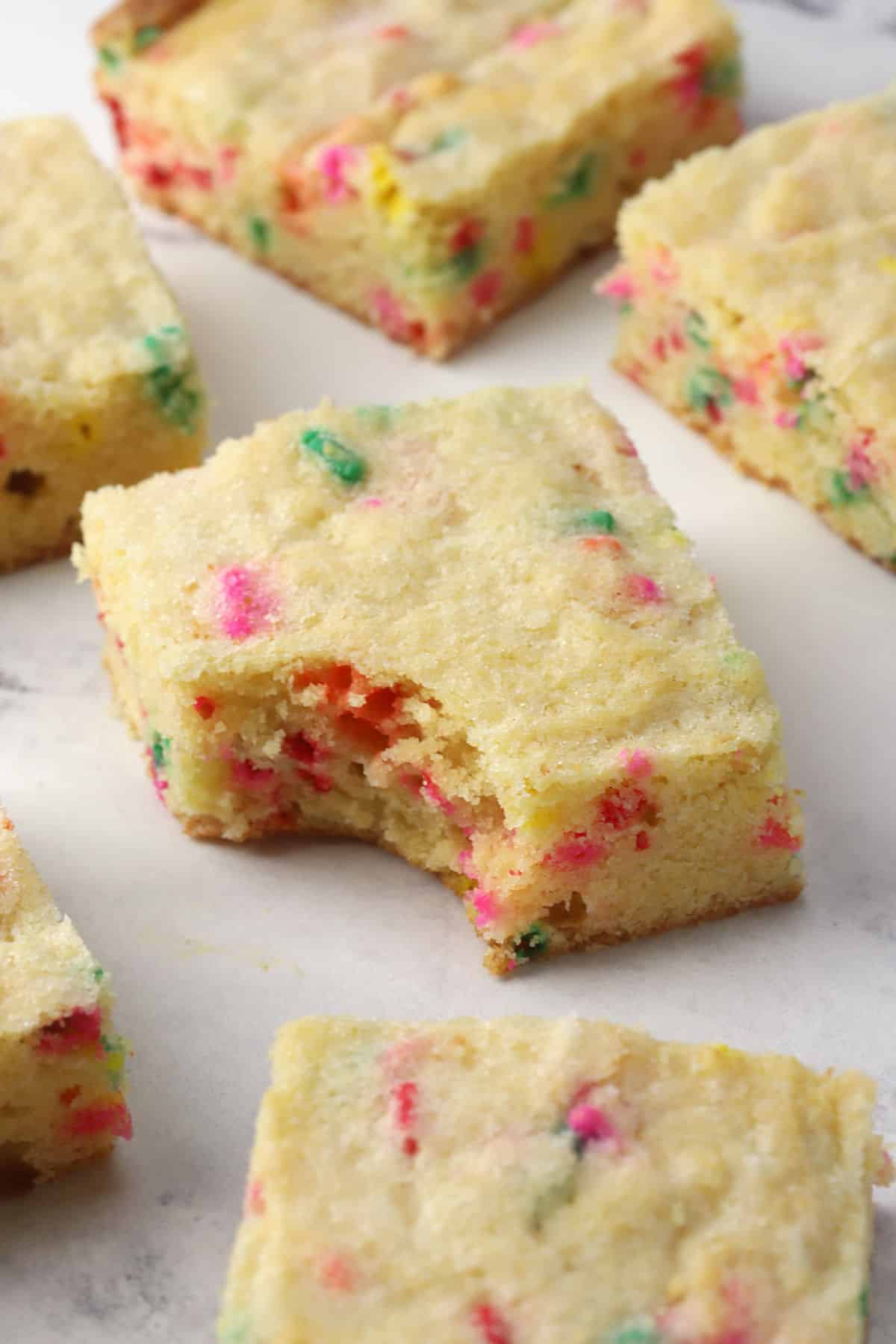 A funfetti sugar cookie square with a bite taken out.