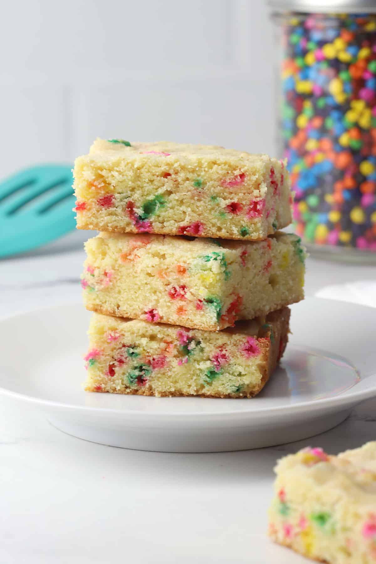 A white plate stacked with funfetti sugar cookie bars.