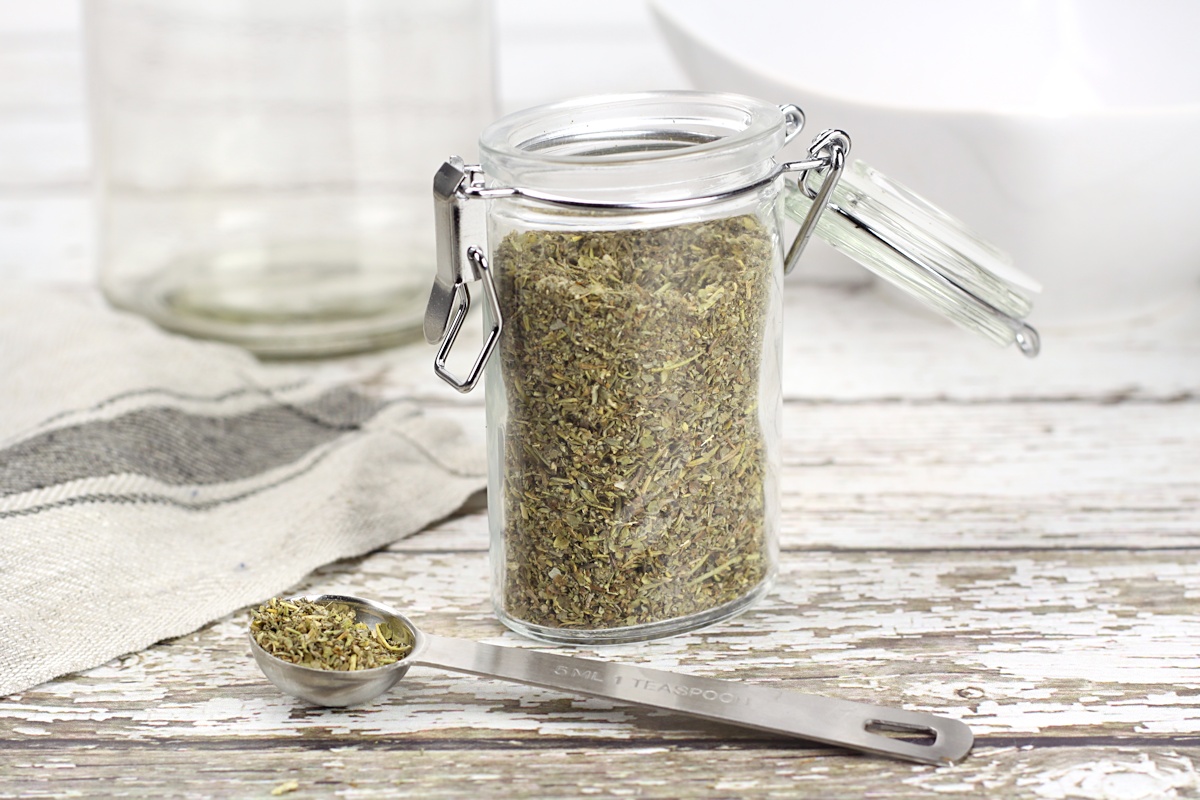 A glass spice jar with a metal measuring spoon.