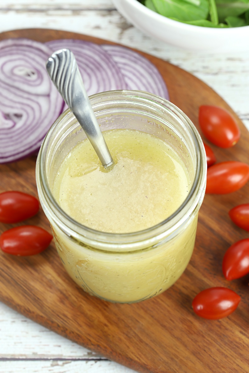 Close up of vinaigrette in a mason jar with a metal spoon.