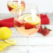 A wine glass filled with Rosé Sangria, with strawberries and lemon slices