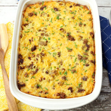 9x13 pan of breakfast casserole with yellow and blue kitchen towels and a wooden server