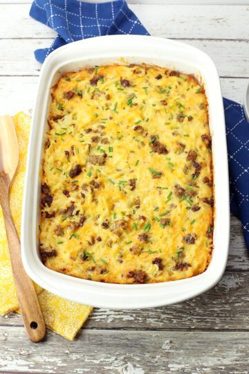 9x13 pan of breakfast casserole with yellow and blue kitchen towels and a wooden server