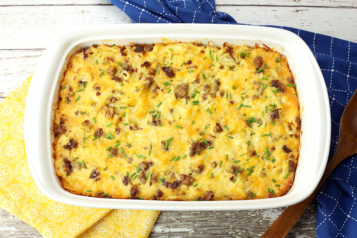 White casserole dish filled with hash browns, eggs, cheese, and sausage