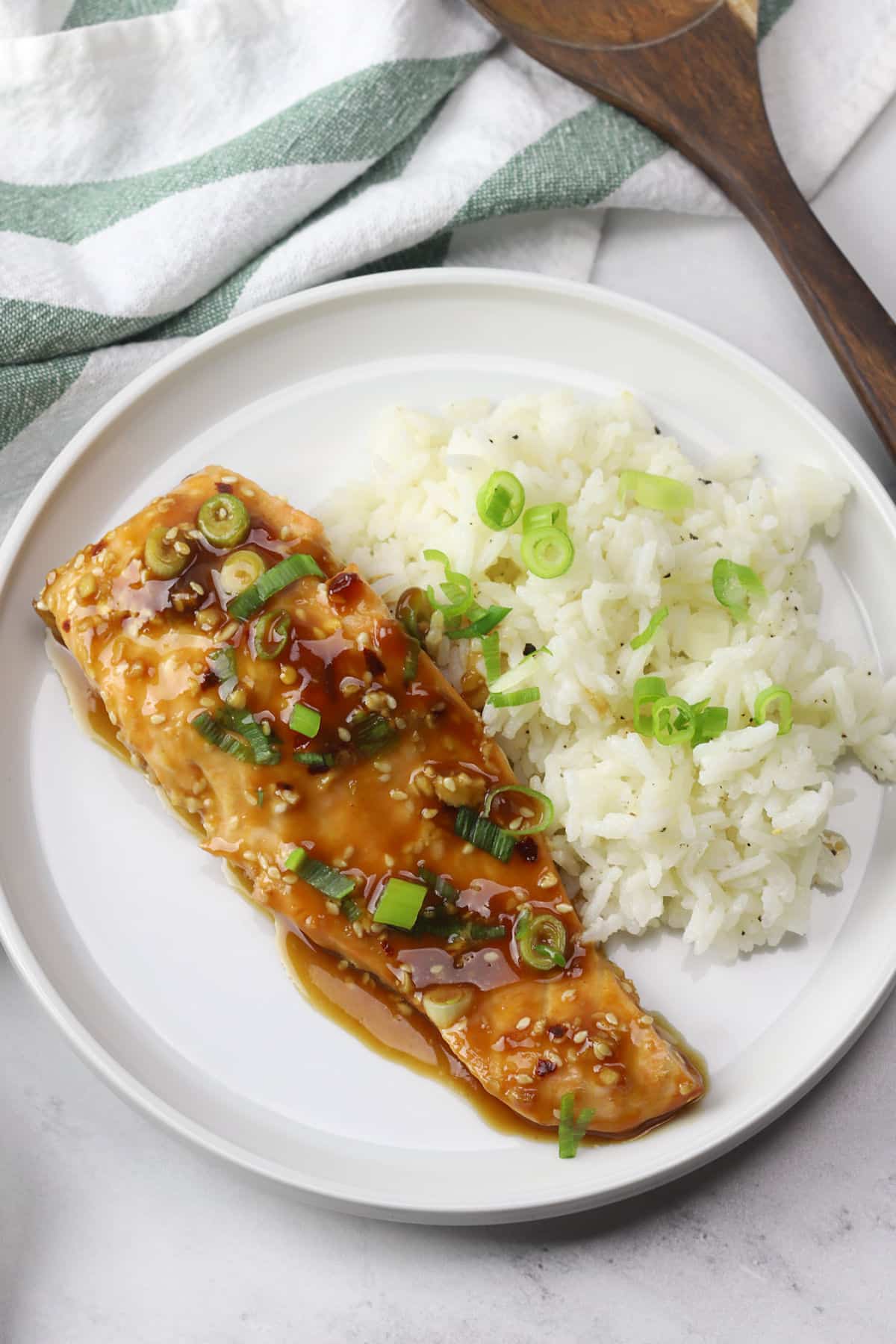 A round white plate with teriyaki salmon and white rice.