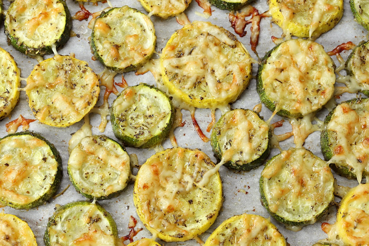 Zucchini and yellow squash sliced into discs and spread onto a sheet pan.