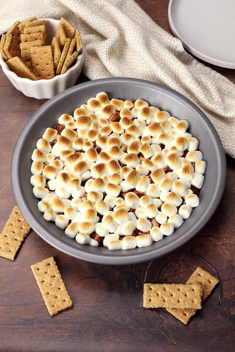 S'mores dip in a pie pan with graham crackers ready for dipping.
