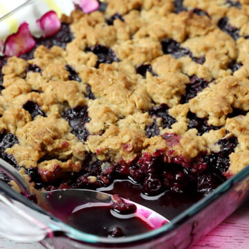 A metal spoon scoops out a serving of blueberry crisp.