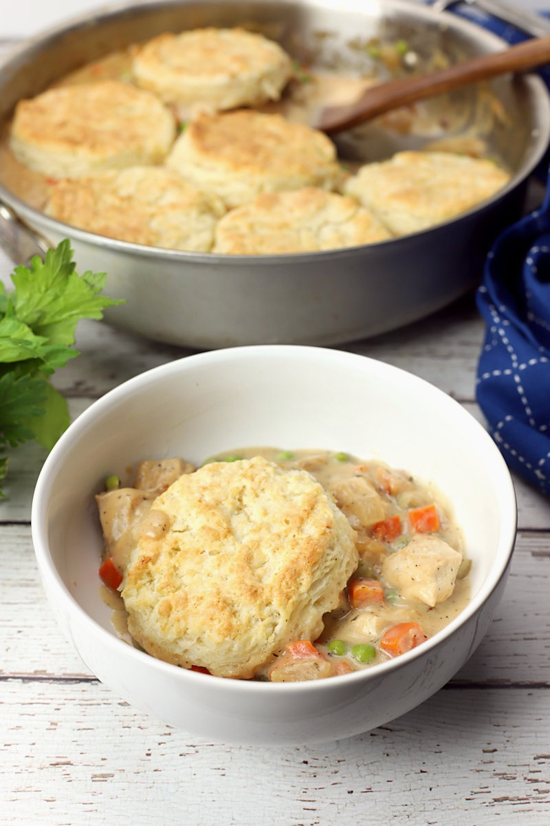 A serving of chicken pot pie with biscuits in a white bowl.