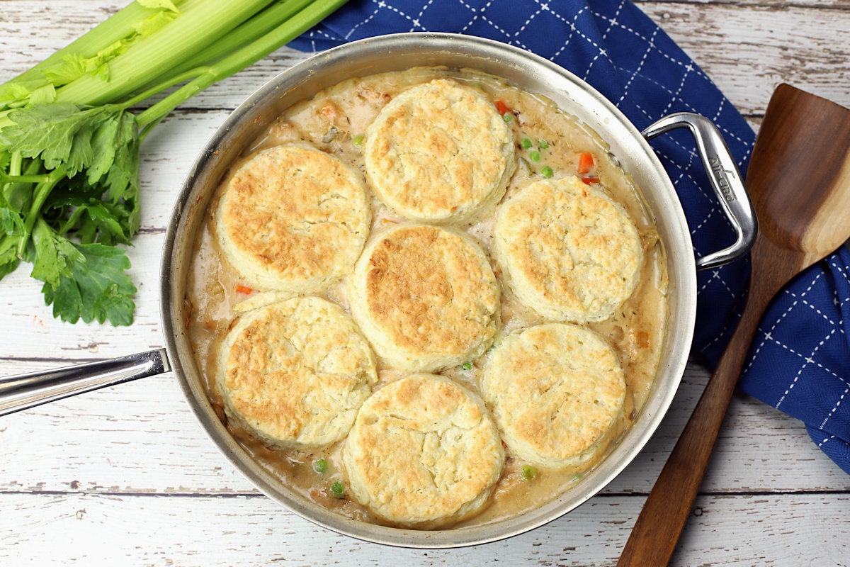 Saute pan filled with chicken pot pie with biscuits, on a white counter top.