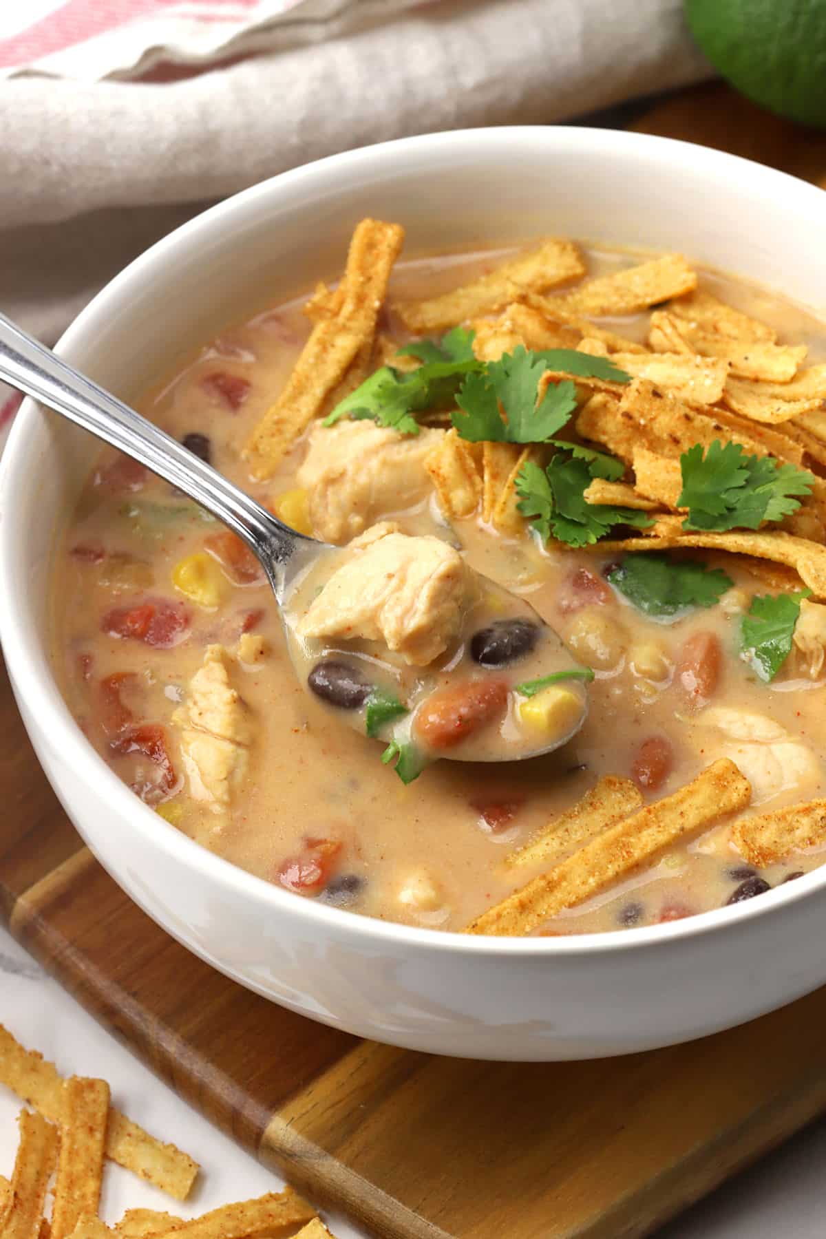 Bowl of creamy chicken tortilla soup with cilantro and tortilla strips sprinkled on top.