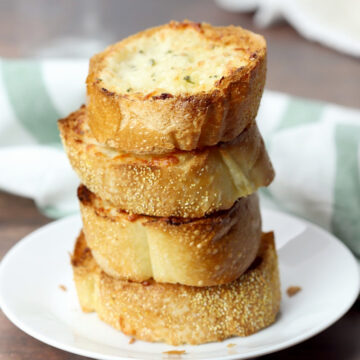 A stack of garlic bread on a white plate.