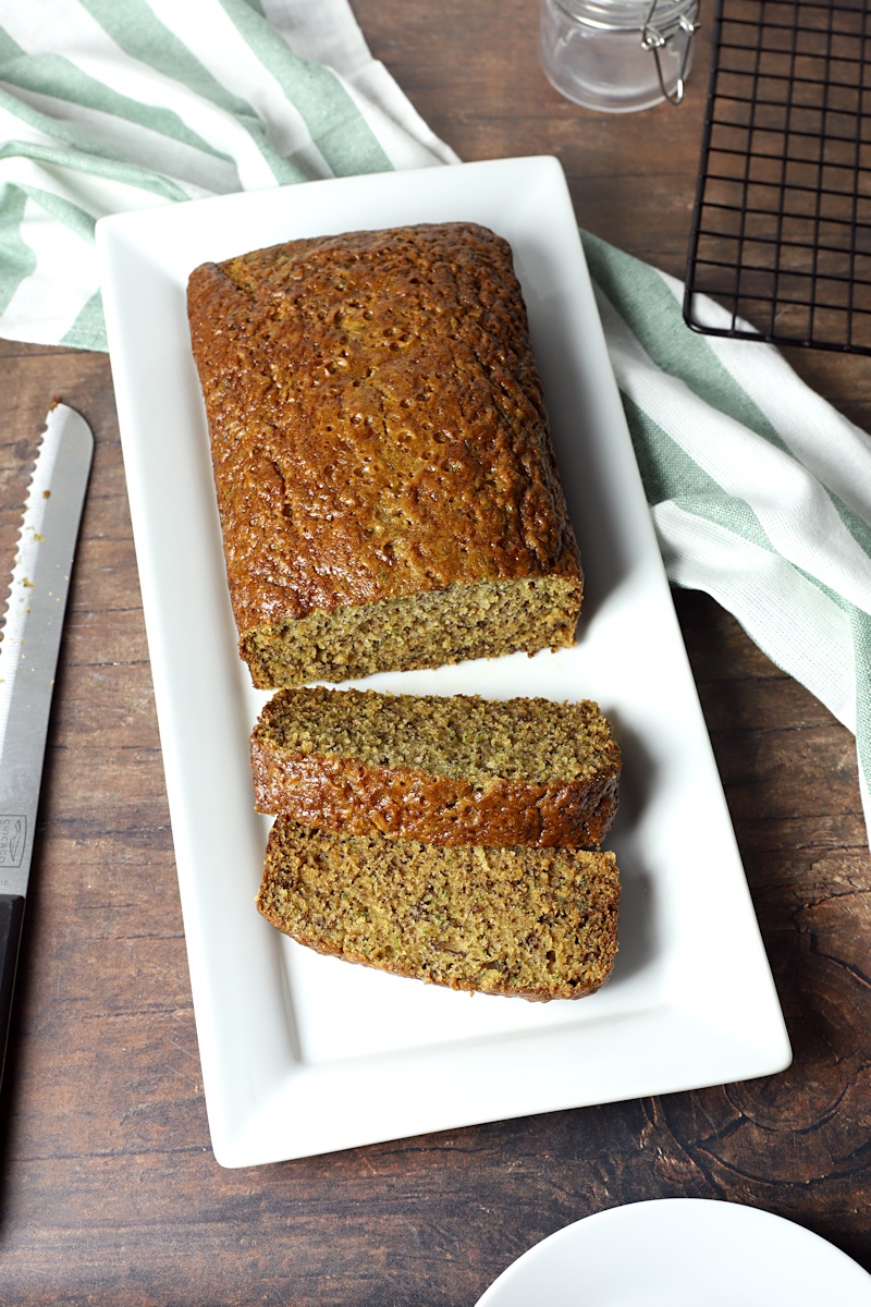 A loaf of bread on a serving plate with bread knife.