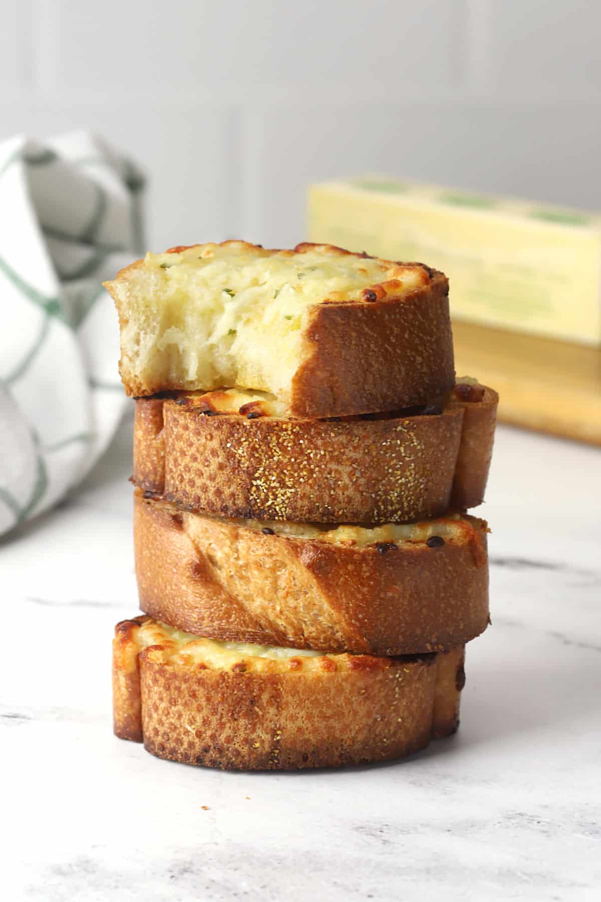 A stack of cheesy garlic bread slices on a countertop.
