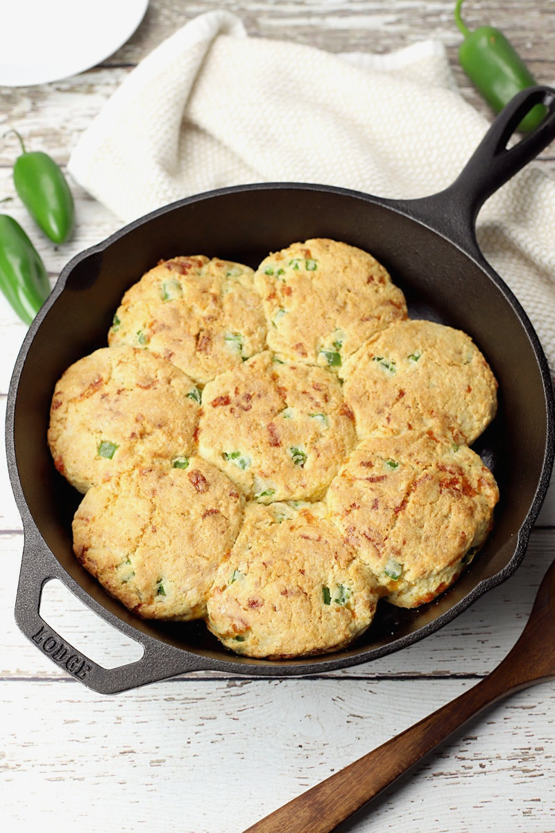 A cast iron skillet filled with jalapeno cheddar biscuits.