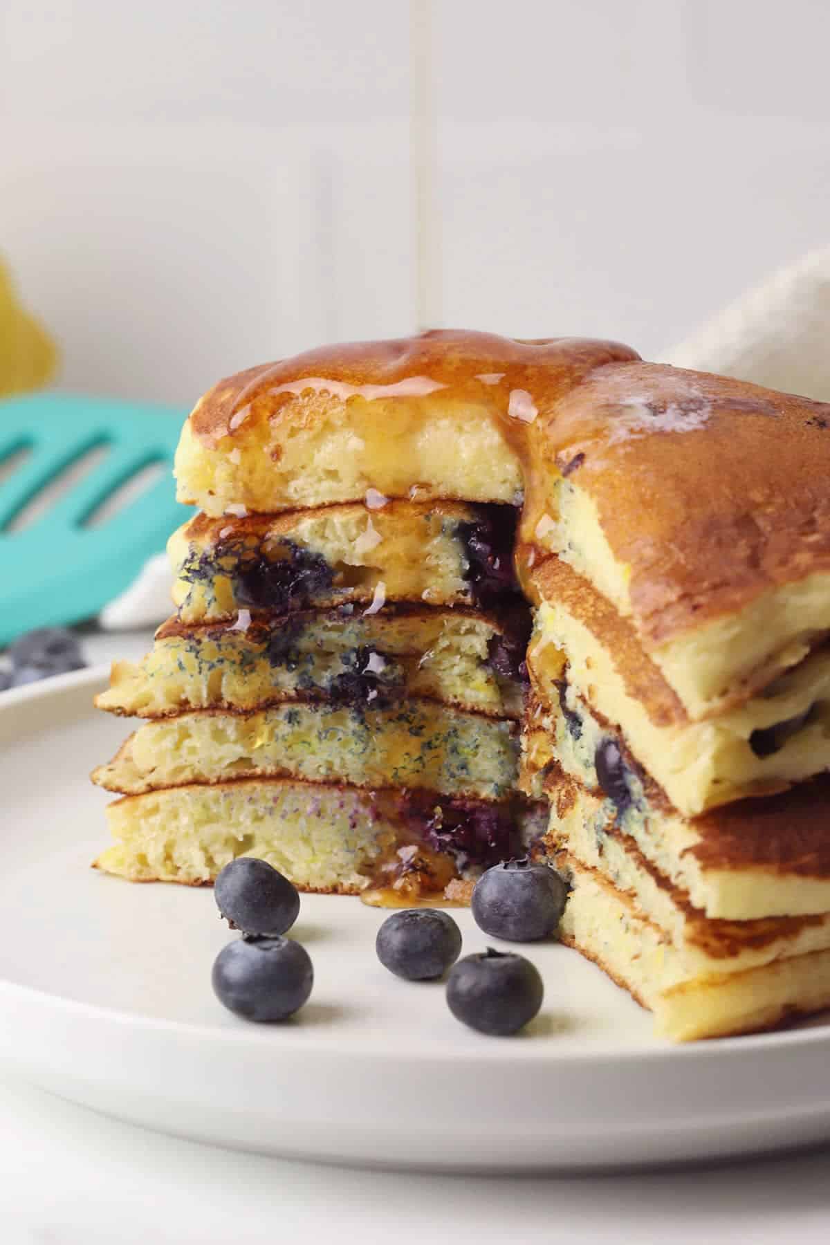 Sliced blueberry pancakes with maple syrup being poured on top.