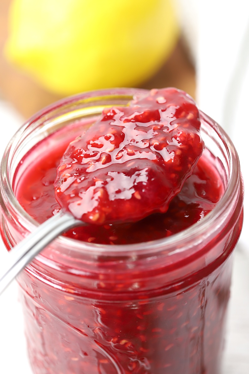 A spoon of jam on top of a jar.