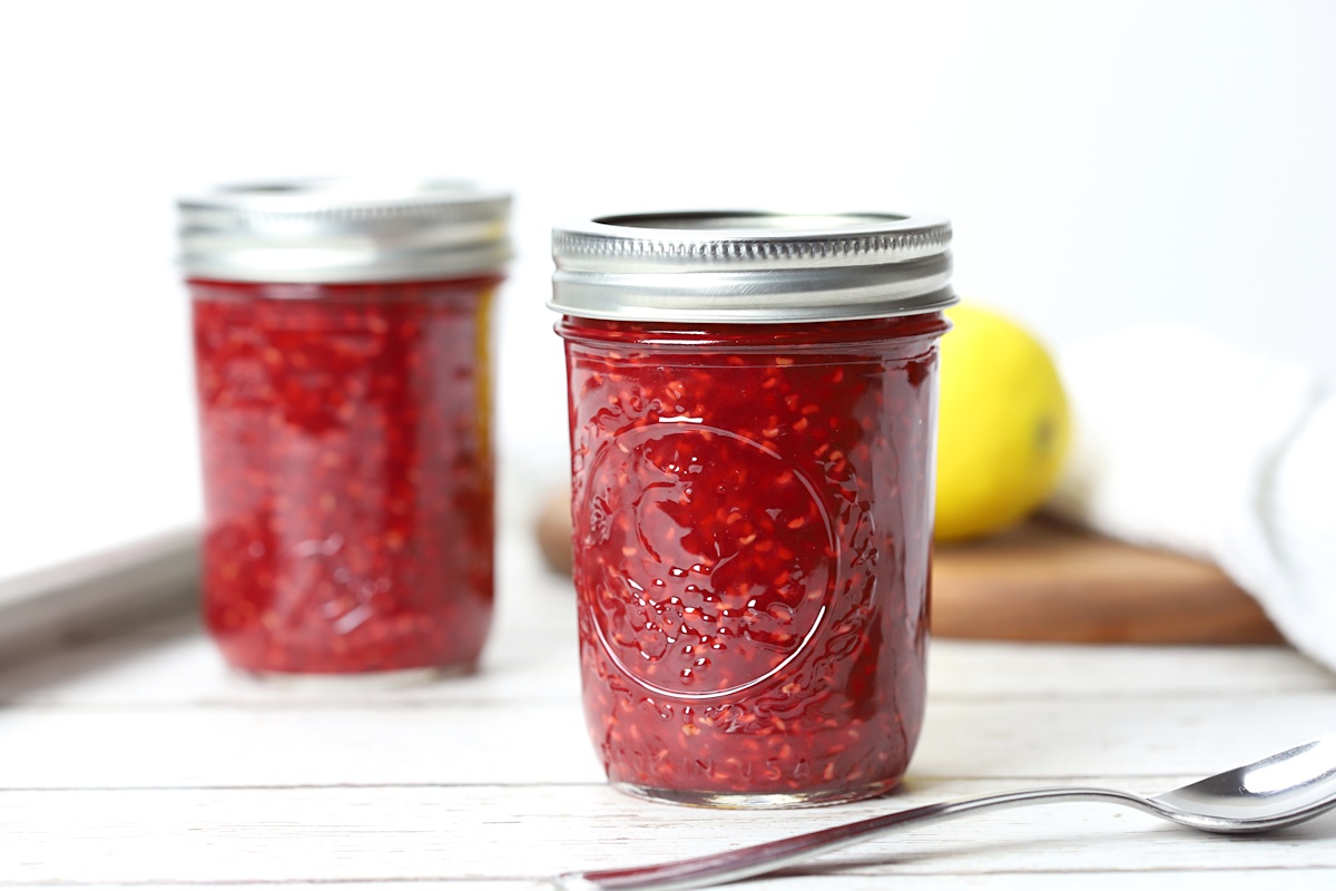 Jars of freezer jam on a white wood counter top.