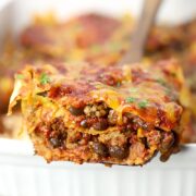 Serving of beef enchilada casserole on a wooden serving spatula.