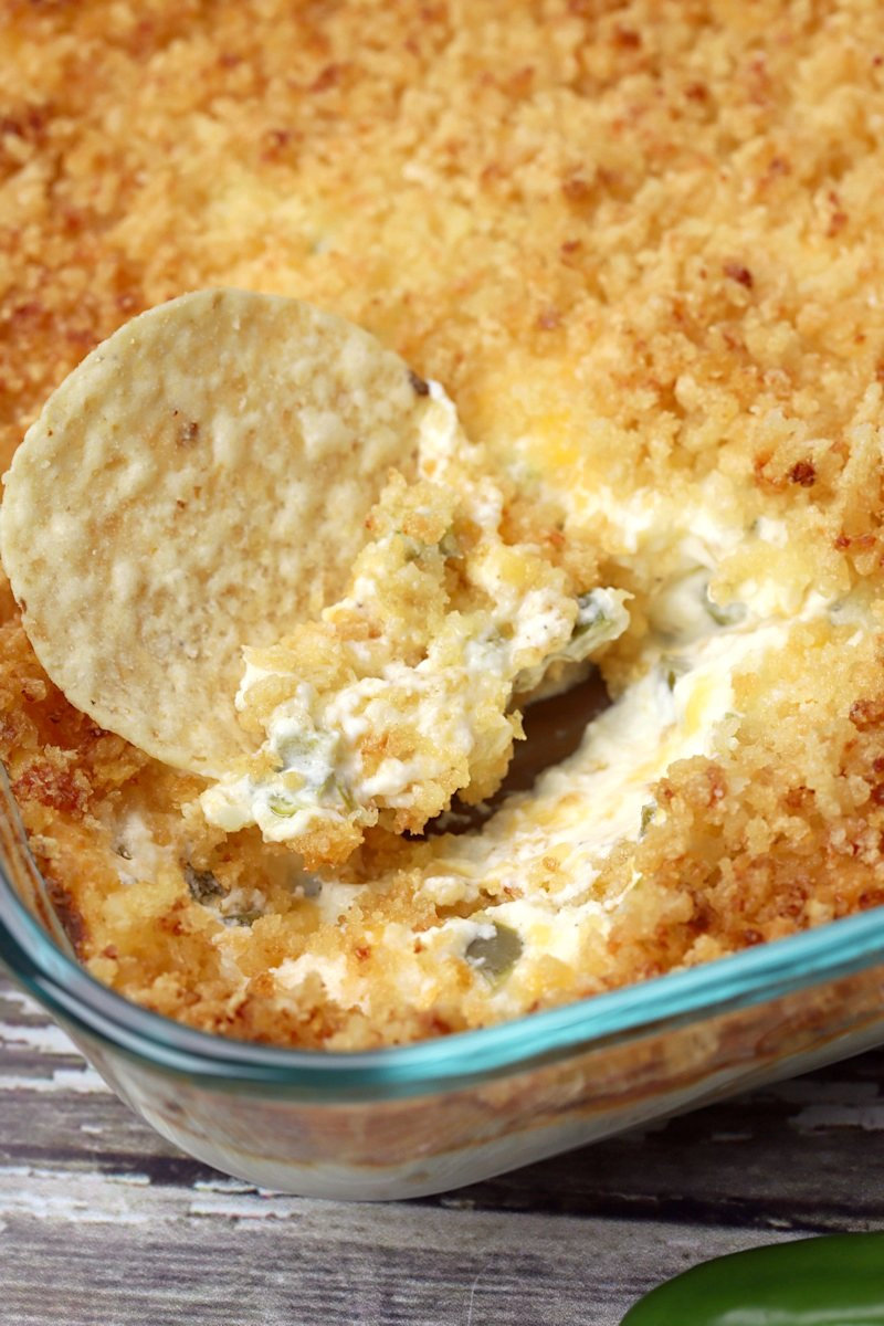 A tortilla chip in a dish of jalapeno popper dip.