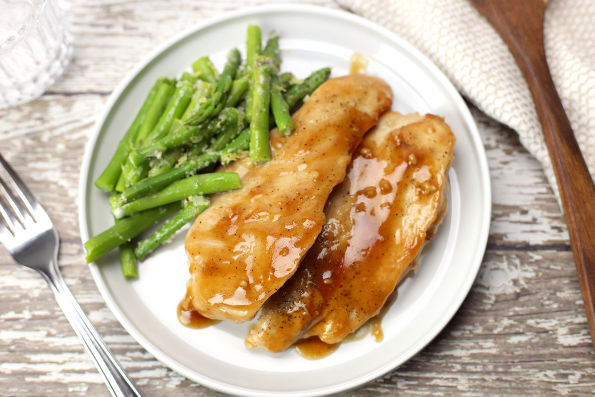 Maple glazed chicken with asparagus on a white plate.