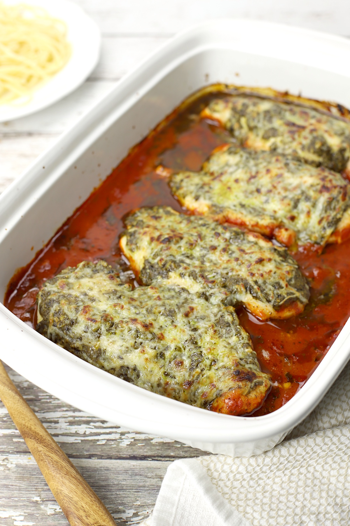 Pesto mozzarella chicken with marinara sauce in a large baking dish.