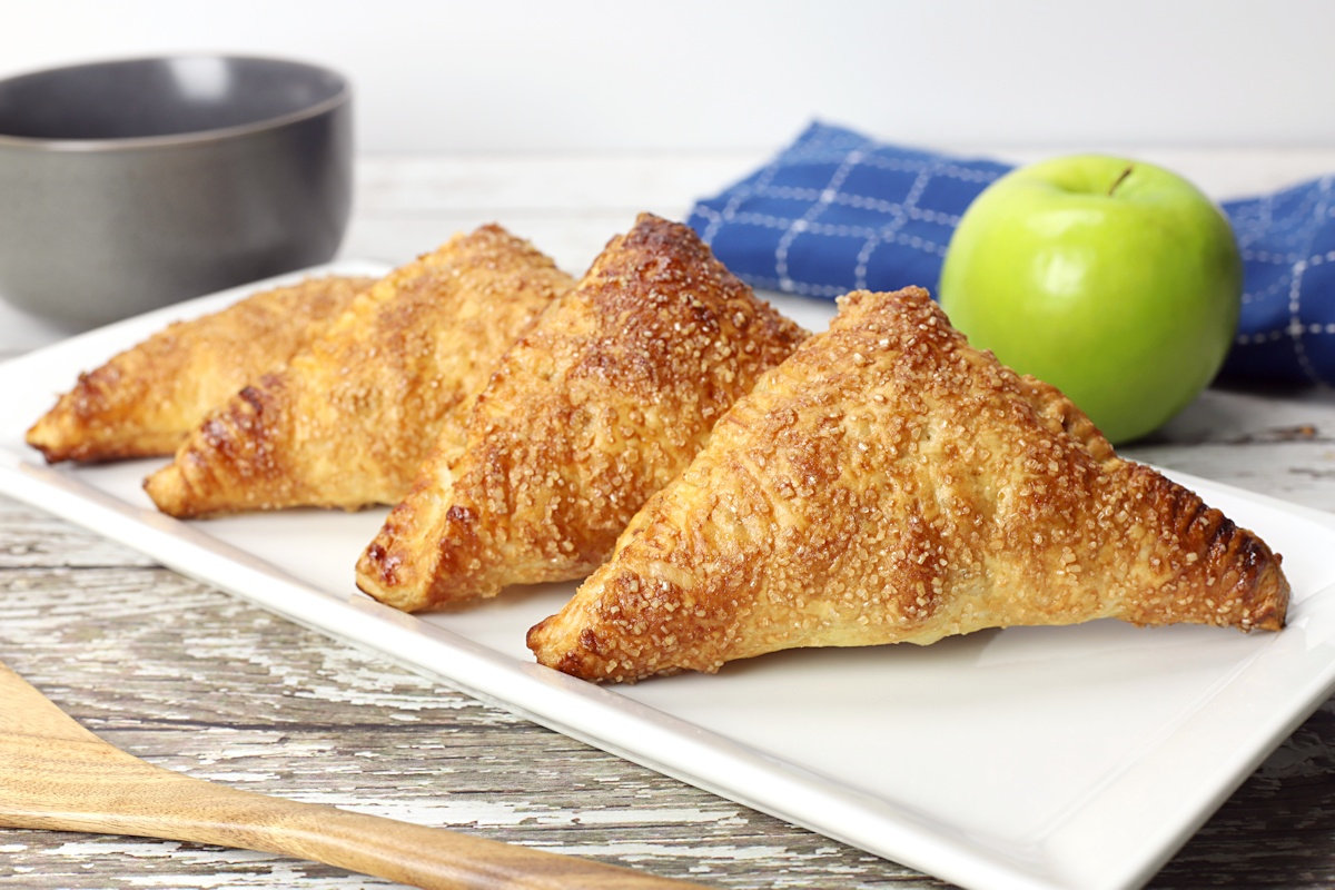 Plate of puff pastry apple turnovers on a wood counter top.