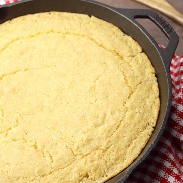 A round cast iron skillet filled with baked cornbread.