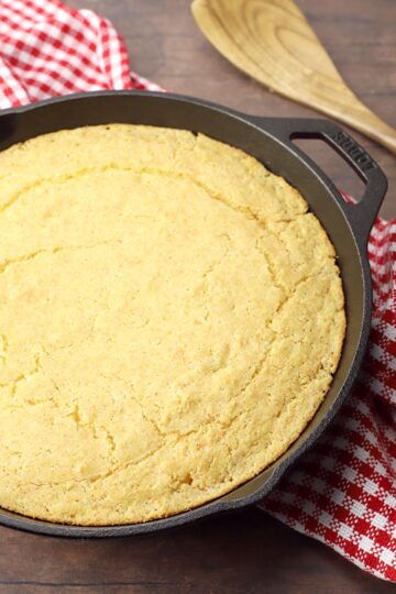 A round cast iron skillet filled with baked cornbread.
