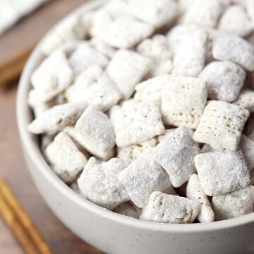 Puppy chow in a bowl on a wooden counter top.