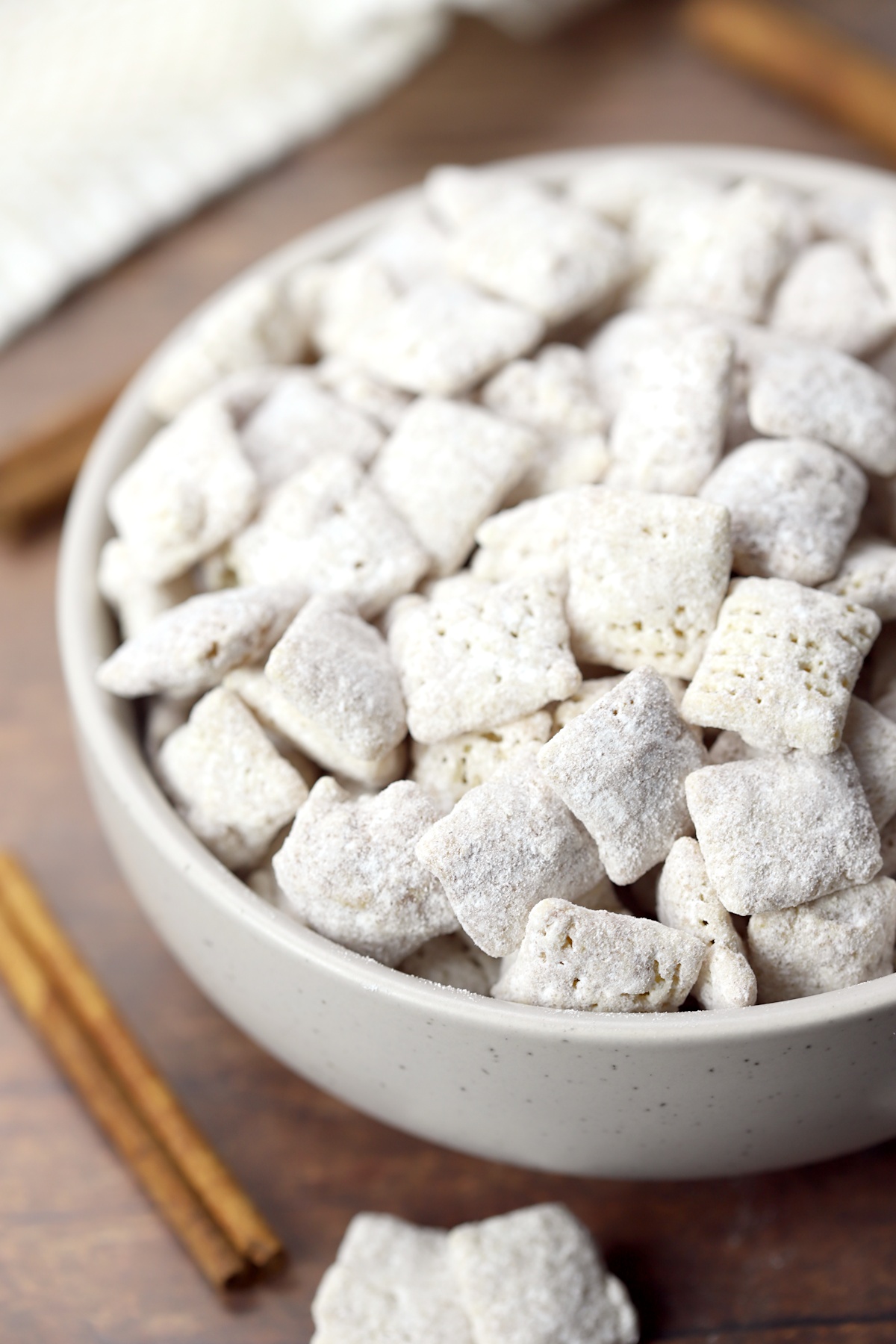 Puppy chow in a bowl on a wooden counter top.