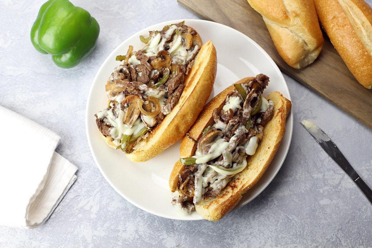 Two steak sandwiches on a white plate.