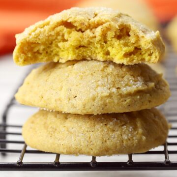 Stack of pumpkin sugar cookies on the edge of a cooling rack.