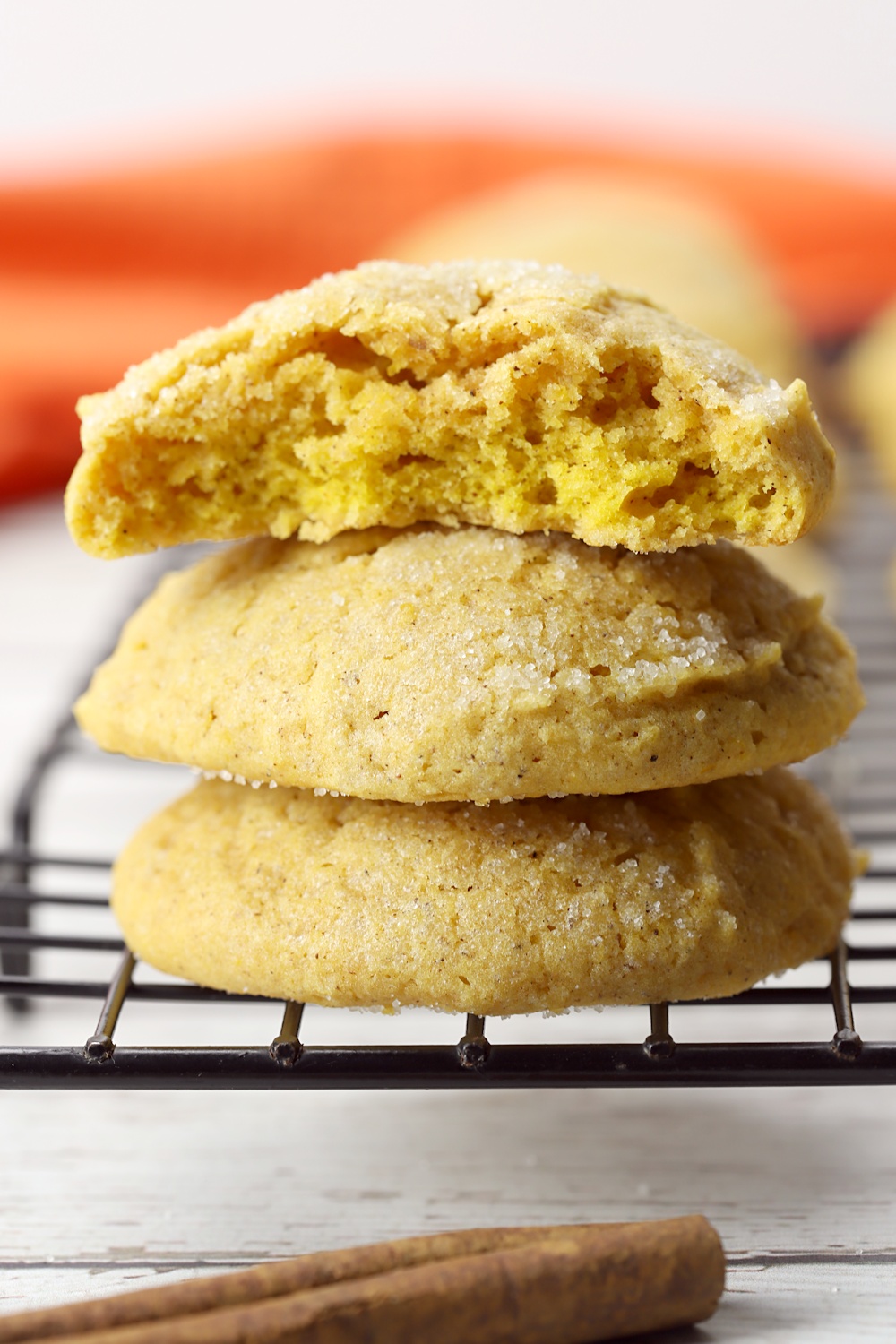 Stack of pumpkin sugar cookies on the edge of a cooling rack.