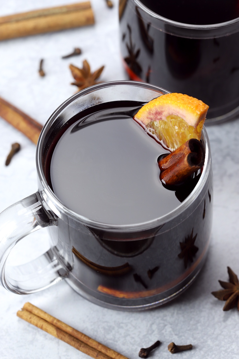 An orange slice and cinnamon stick in a glass of mulled wine. 