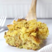 Wooden spatula holding a serving of cornbread dressing.