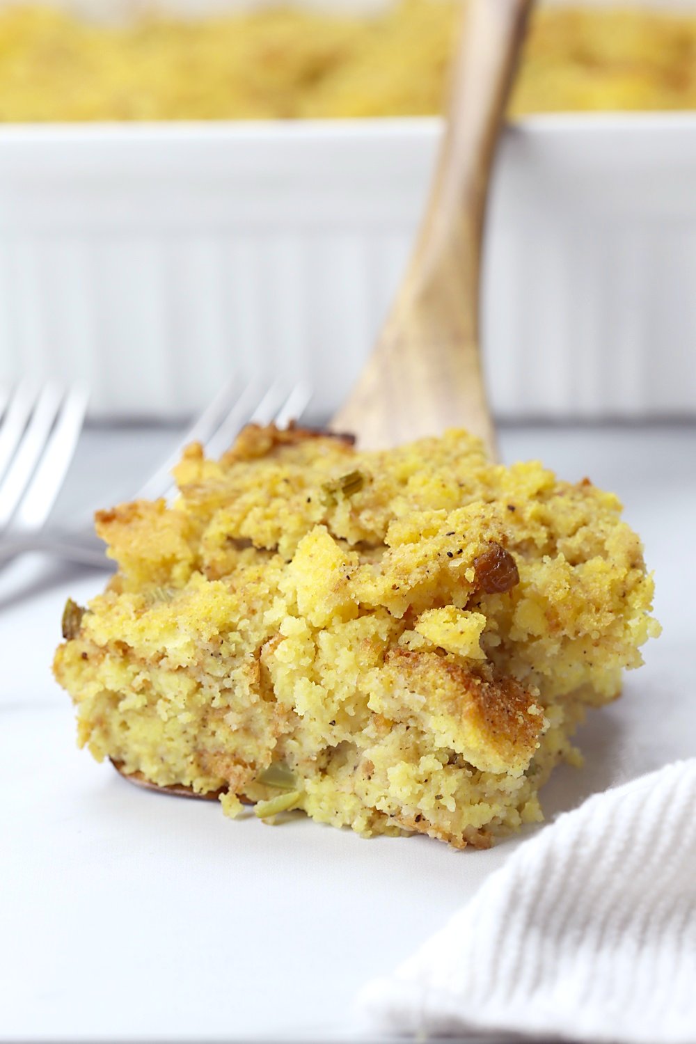 Wooden spatula holding a serving of cornbread dressing.