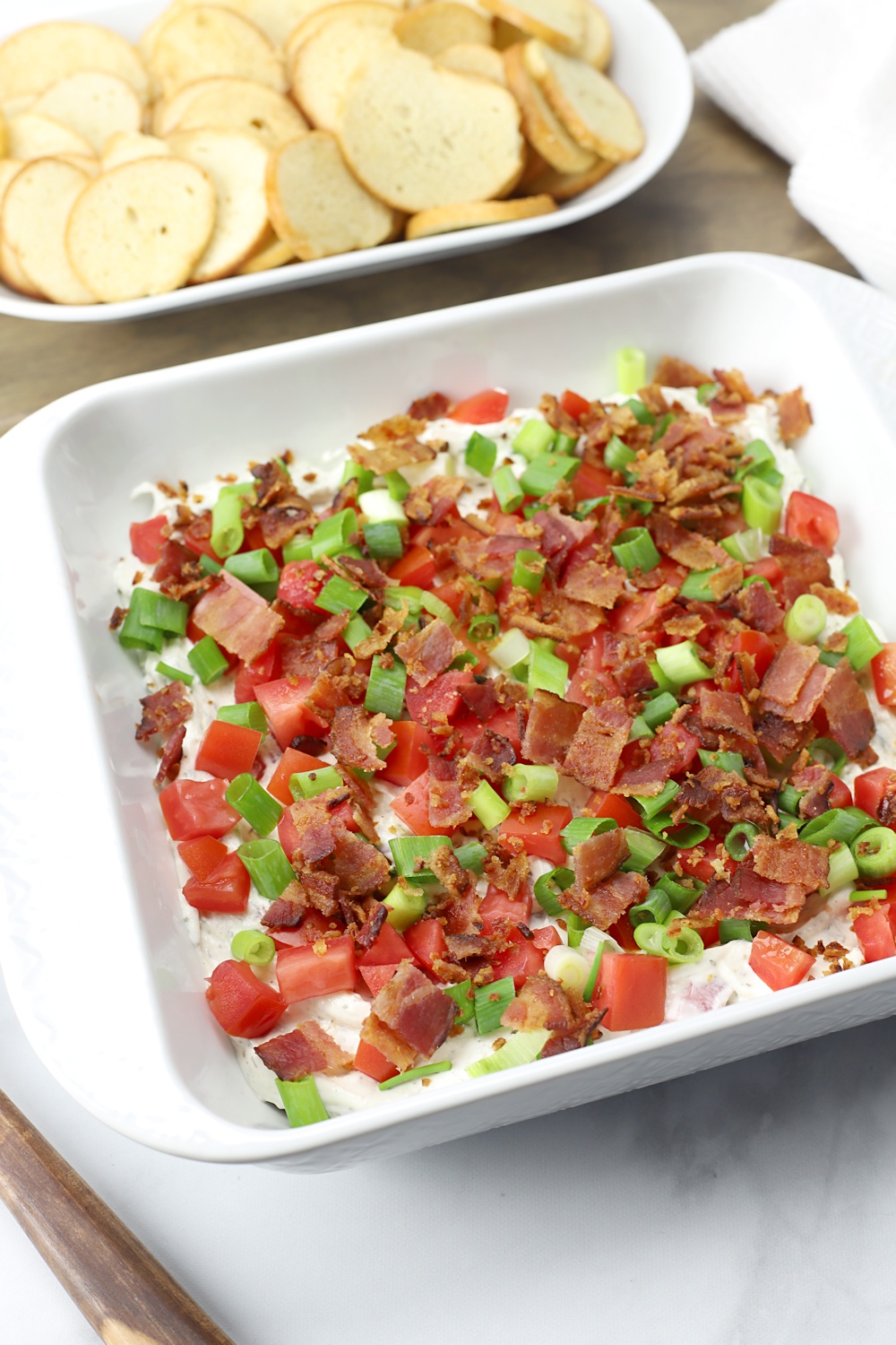A plate of BLT Dip with bagel chips, ready to serve.