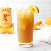 A glass of fireball orange sweet tea on a marble counter top.