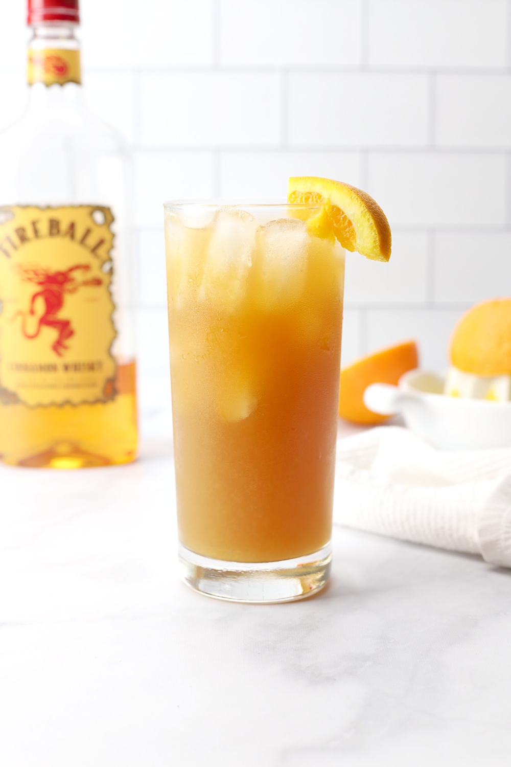 A glass of fireball orange sweet tea on a marble counter top.
