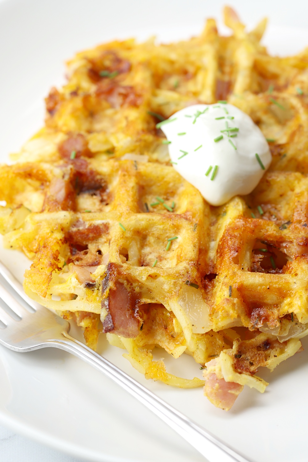 Dollop of sour cream and chives on top of savory waffles.