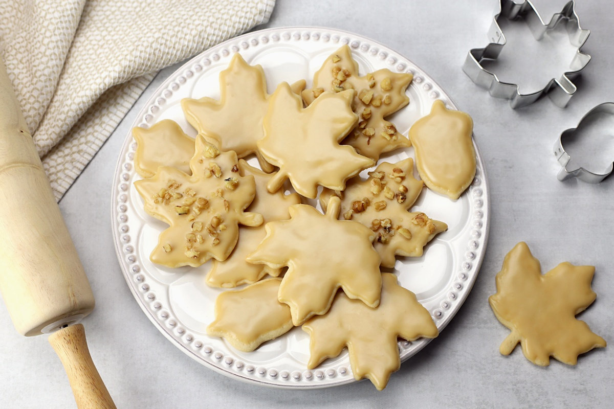 A decorative plate filled with maple leaf cut out cookies.