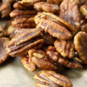 Stovetop candied pecans on a wooden cutting board.