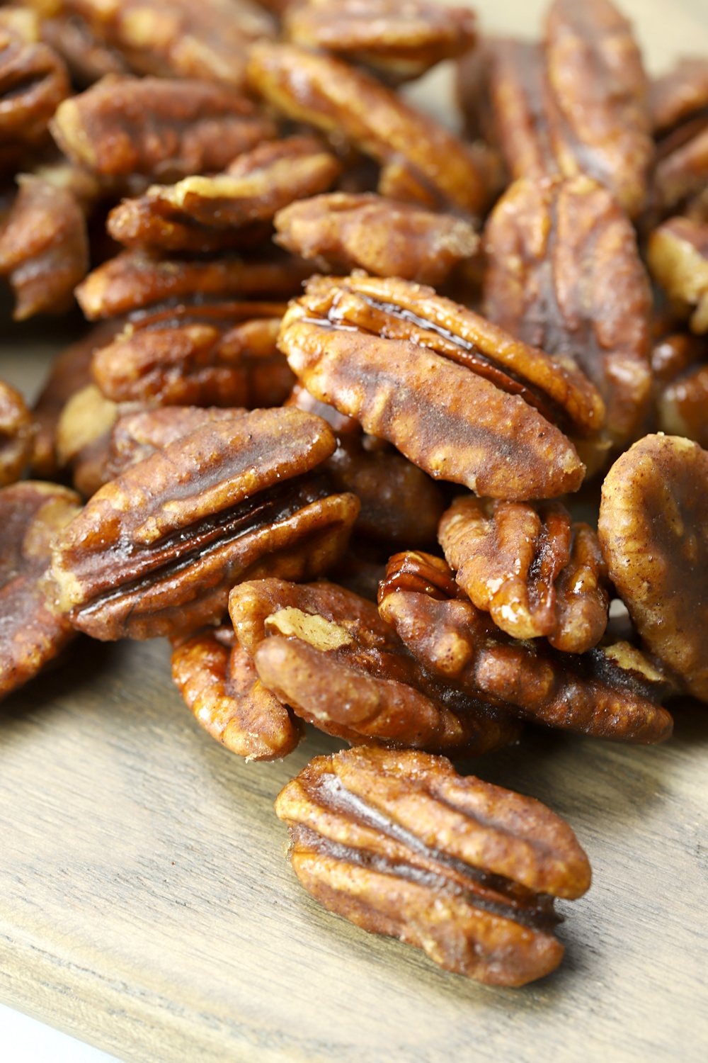 Stovetop candied pecans on a wooden cutting board.