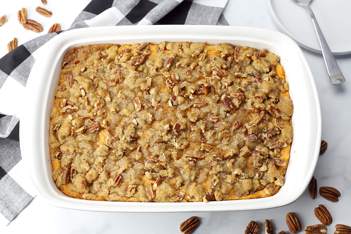 Sweet potato casserole in a white pan with a black and white checkered towel.