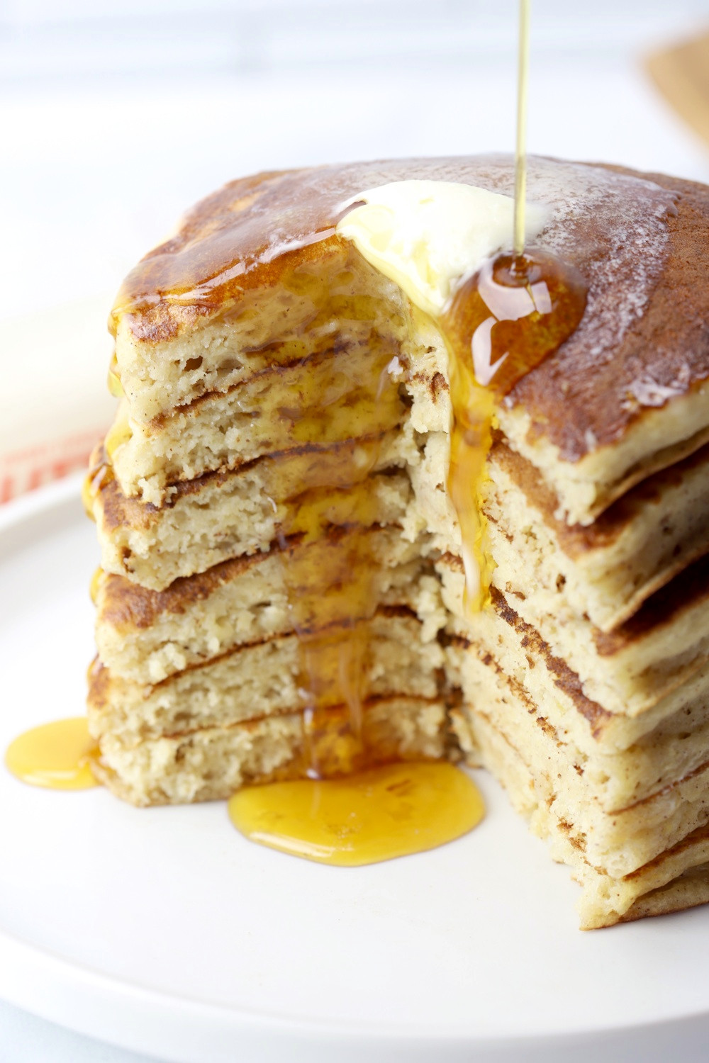 Maple syrup and melting butter dripping down a stack of pancakes.