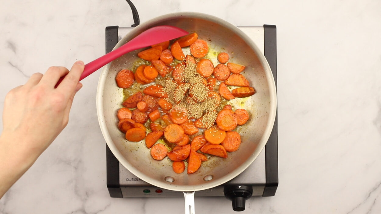 Skillet with carrots and sesame seeds.