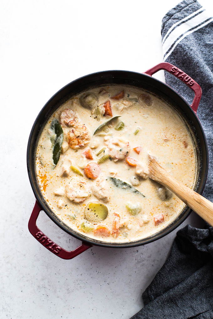 Seafood chowder in a stock pot with a wooden spoon.